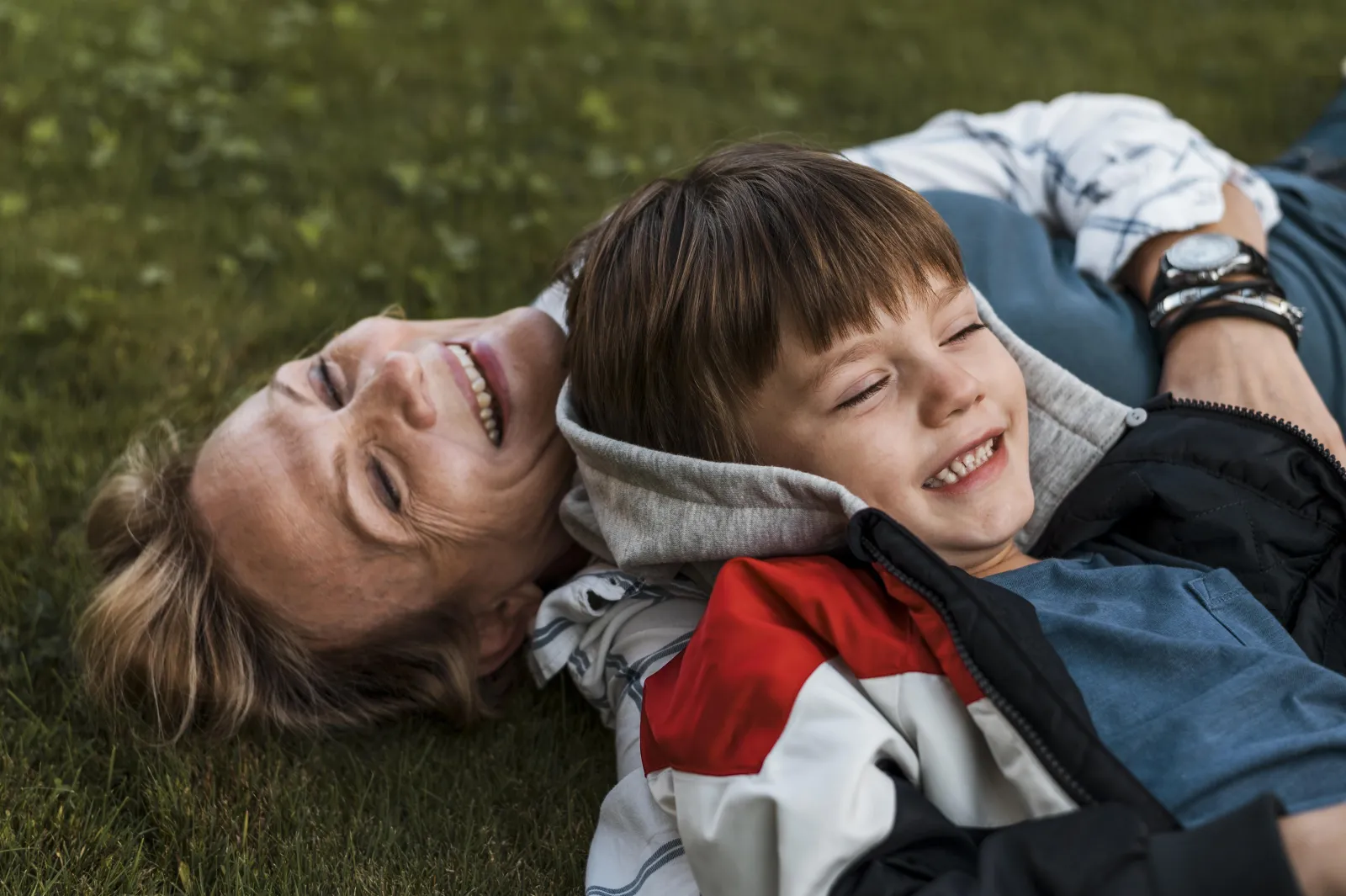 Une mère et son fils rient, allongés dans l’herbe