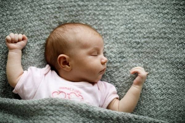 Bébé allongé qui dort la tête tournée sur le côté
